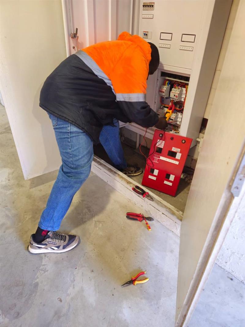 Electrician working carefully inside an open distribution board