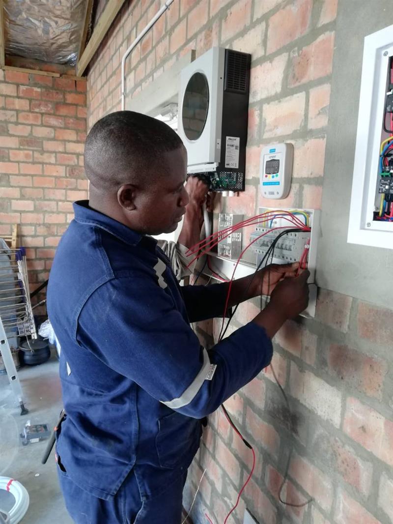 Electrician wiring inverter and electrical equipment on a brick wall