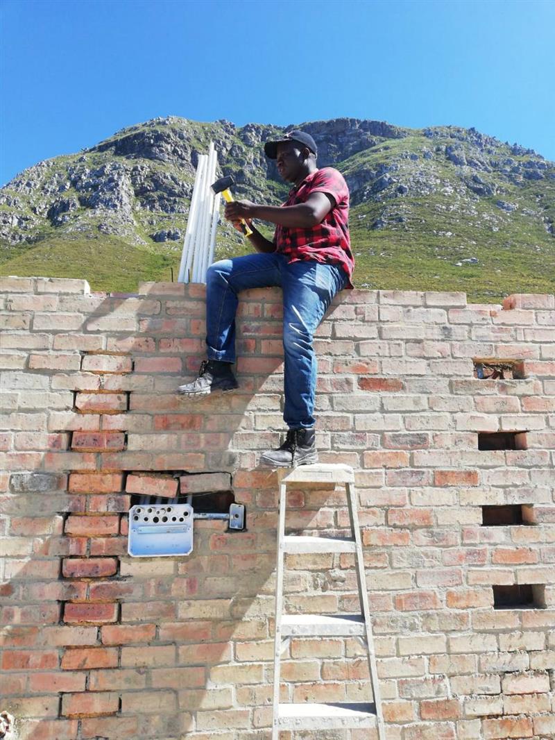 Electrician installing conduit into a brick wall on a new build