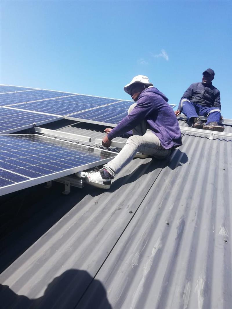Electrical team fitting solar panels on a rooftop